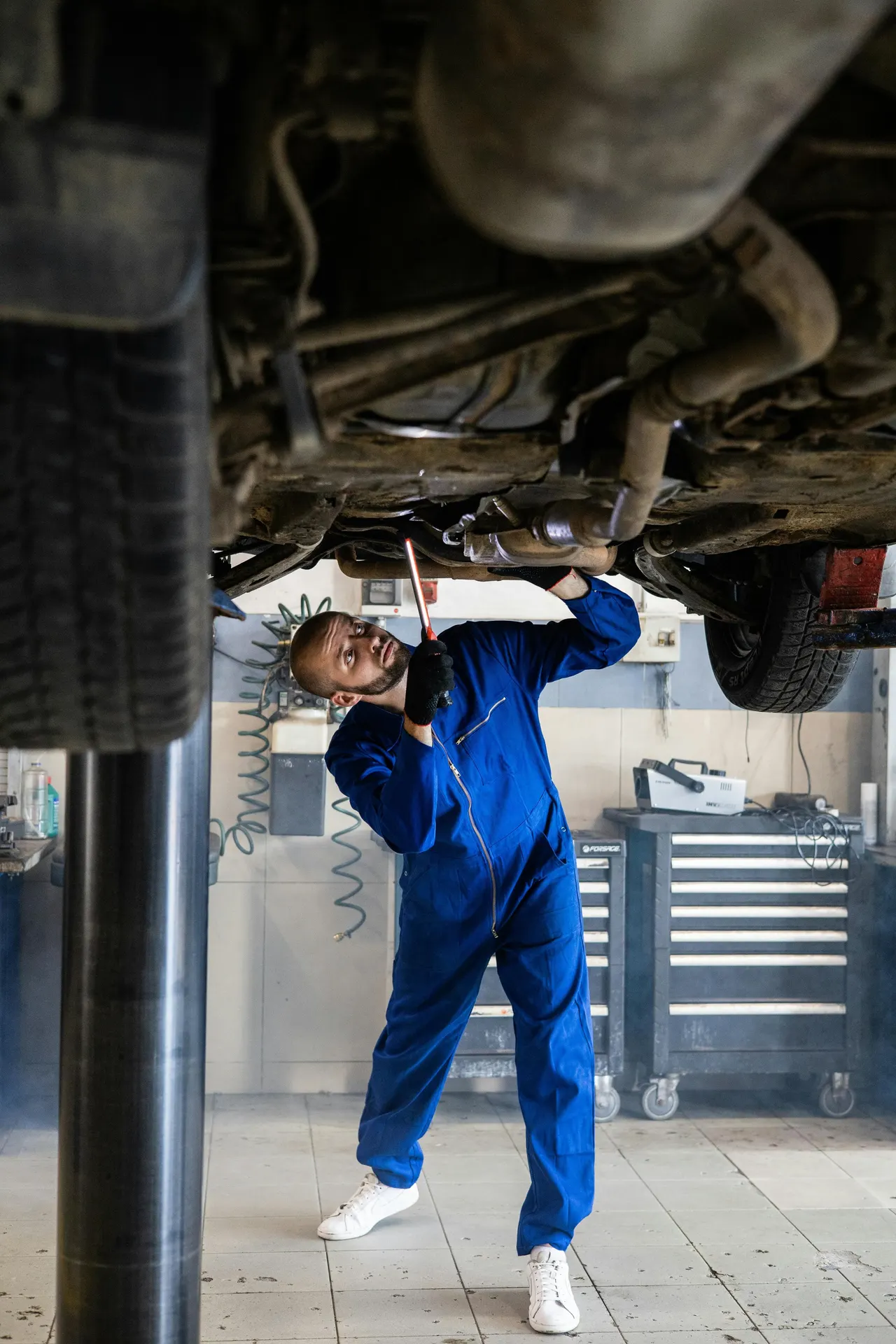 Técnico trabajando bajo un coche levantado en un elevador de taller